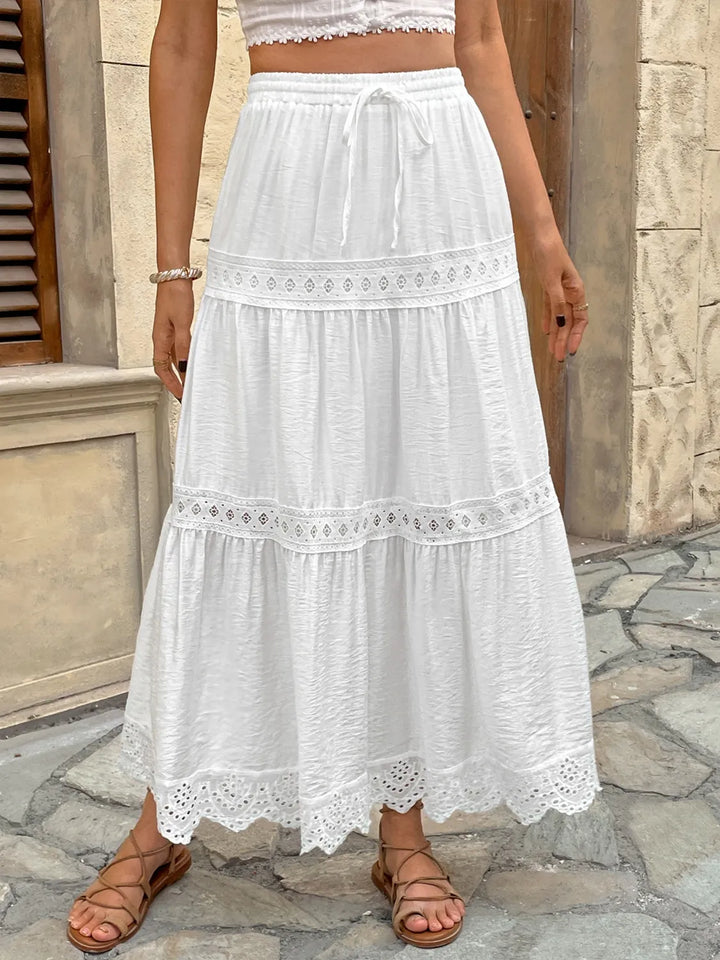 Women's white lace maxi skirt with adjustable tie waist for a bohemian summer look.