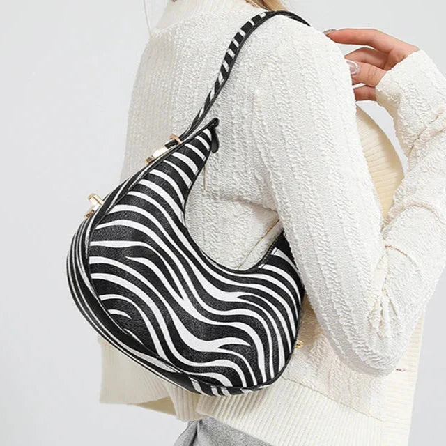 Sophisticated animal print women's crescent bag, faux leather shoulder handbag with a strong zipper closure.
