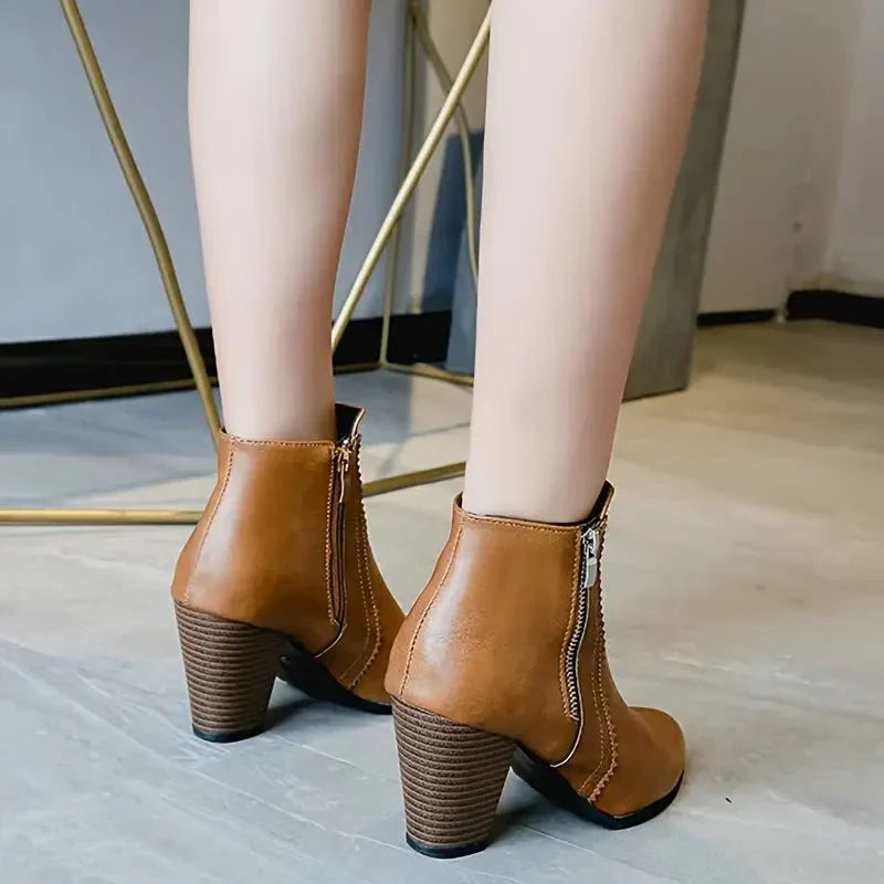Close-up of light brown women's ankle boots: intricate scalloped trim detail & practical side zip closure.