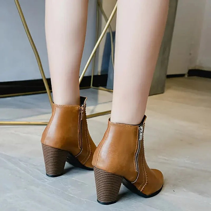 Close-up of light brown women's ankle boots: intricate scalloped trim detail & practical side zip closure.