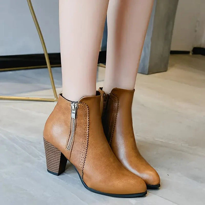 Stylish women's ankle boots in black, showcasing a sturdy block heel, sleek pointed toe & unique scalloped trim.