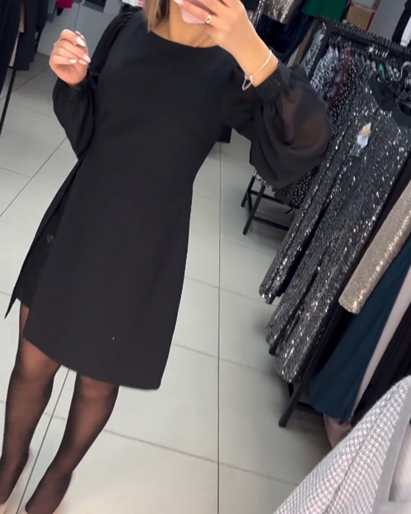 Fashionable women's black mini dress with sheer long sleeves, a sleek slit, and a sophisticated silhouette.