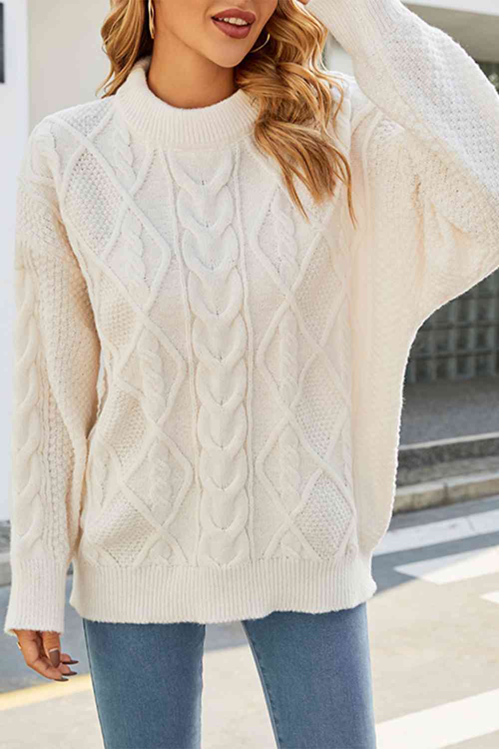 Close-up of a textured women's cable knit jumper, featuring a cozy crew neck and relaxed oversized style.