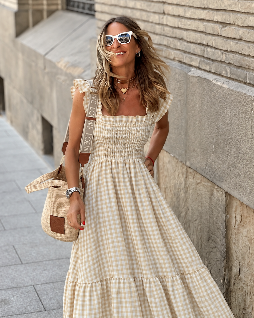 Flowy gingham maxi sundress with smocked bodice and tiered skirt, a stylish option for spring fashion.