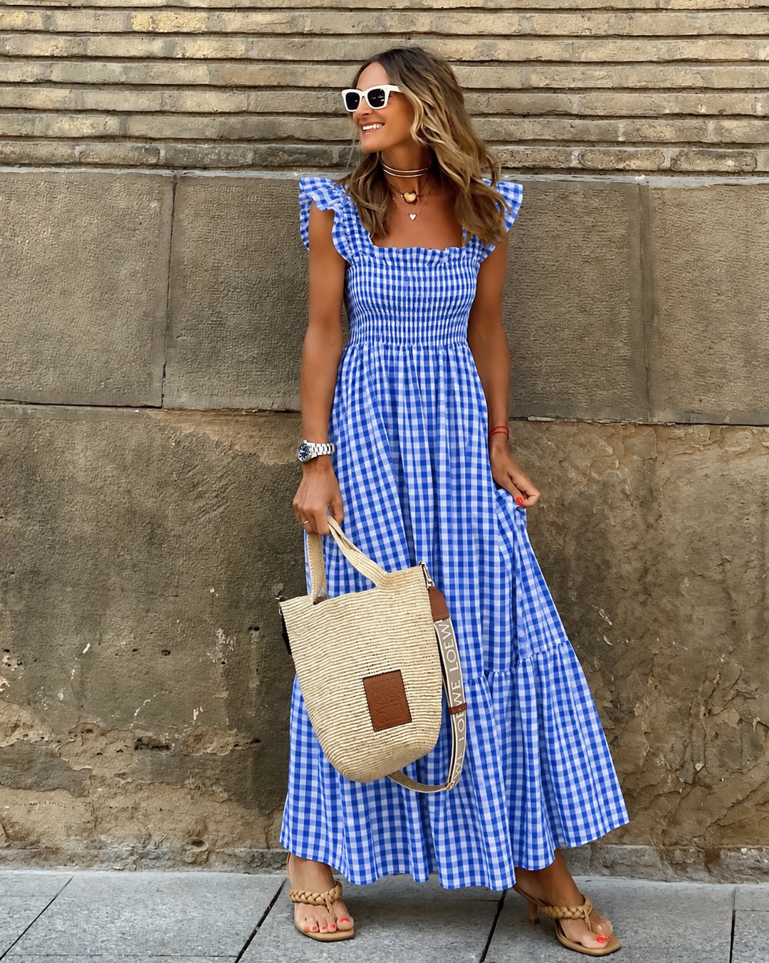 Elegant women's gingham maxi sundress featuring a smocked bodice, flowy tiered skirt, and cap sleeves.