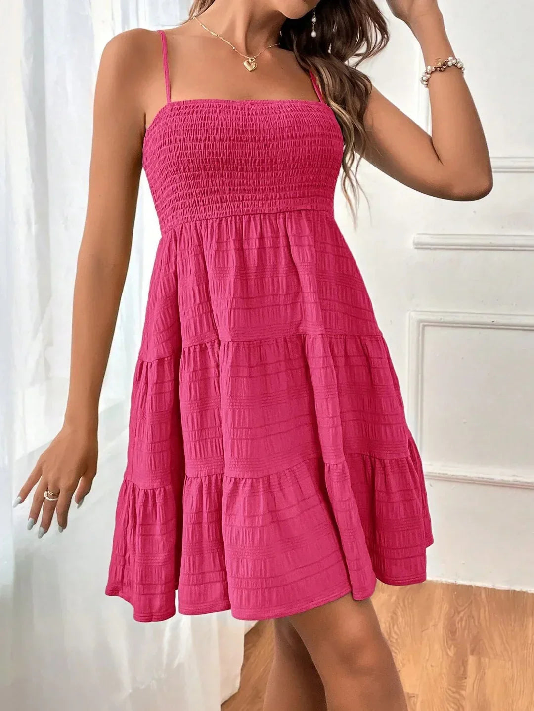 Casual women's smocked mini summer dress with adjustable straps & tiered ruffle hem. Ideal for hot weather.