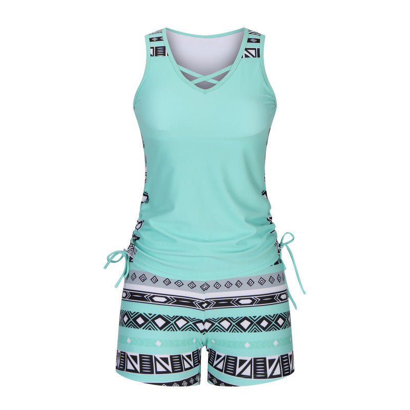 Model in women's criss-cross tankini top & patterned shorts, enjoying a summer beach day.