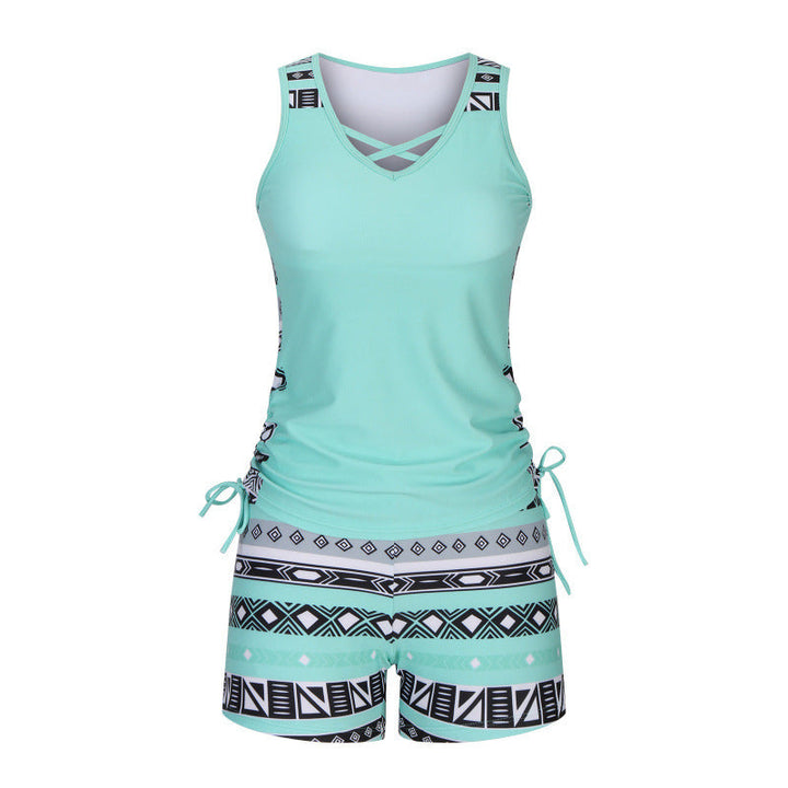 Model in women's criss-cross tankini top & patterned shorts, enjoying a summer beach day.