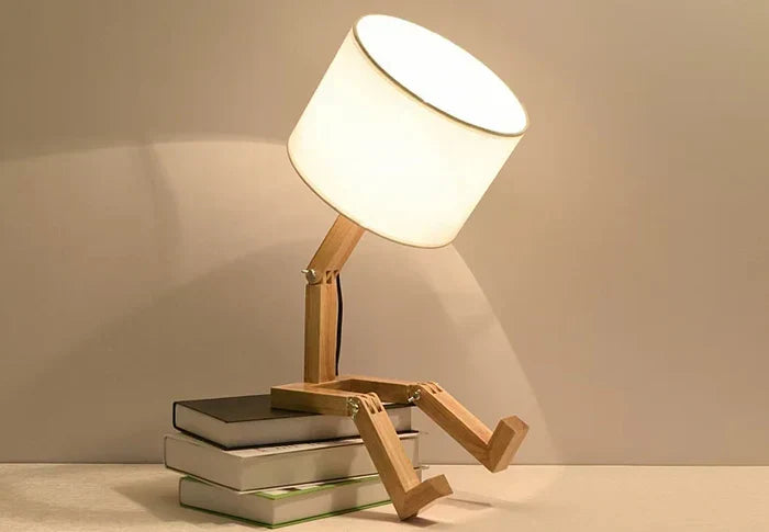 Unique wooden robot desk lamp with fabric shade & convenient book holder. Stylish home decor for modern spaces.