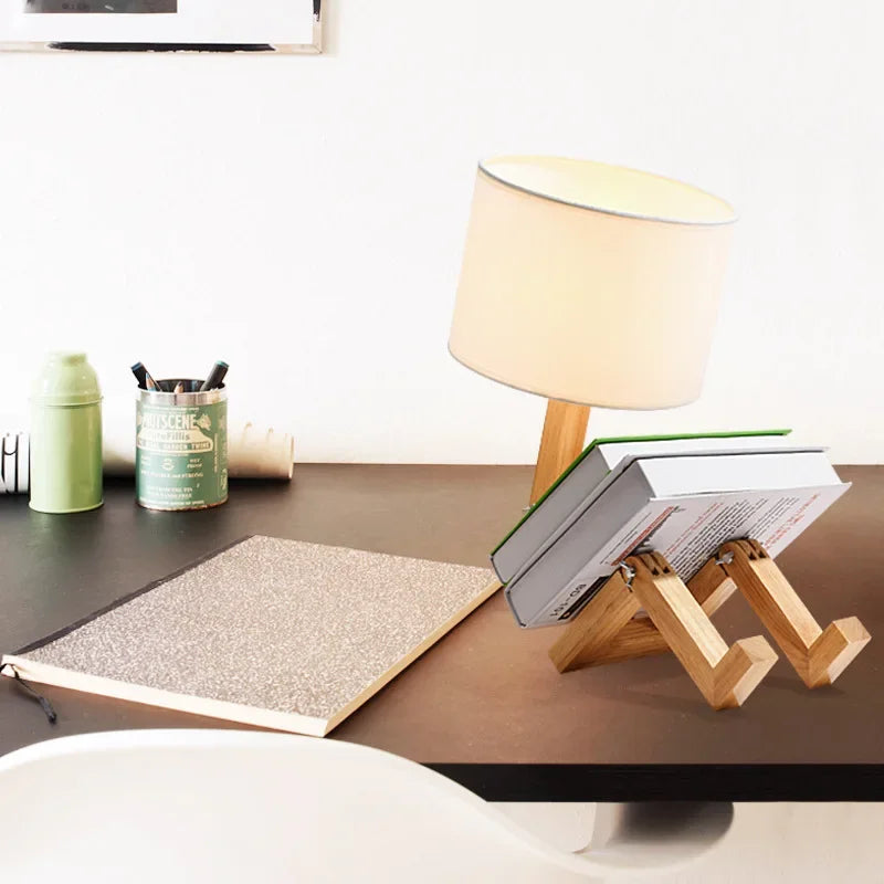 Stylish wood robot lamp with fabric shade & built-in book holder. Modern lighting and decor for any room.