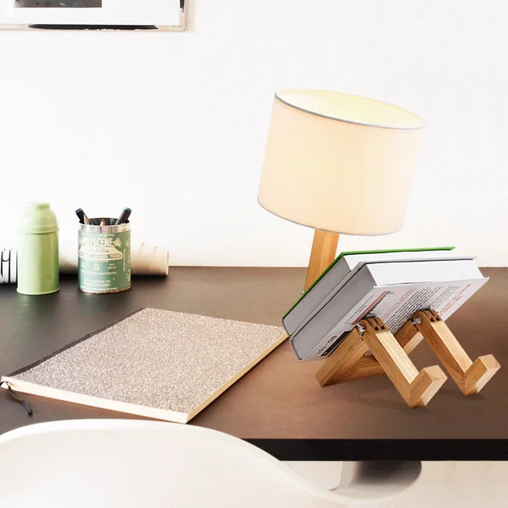Stylish wood robot lamp with fabric shade & built-in book holder. Modern lighting and decor for any room.