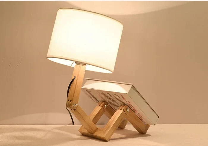 Modern wooden robot table lamp with adjustable arms & integrated book holder. Perfect for reading or desk.